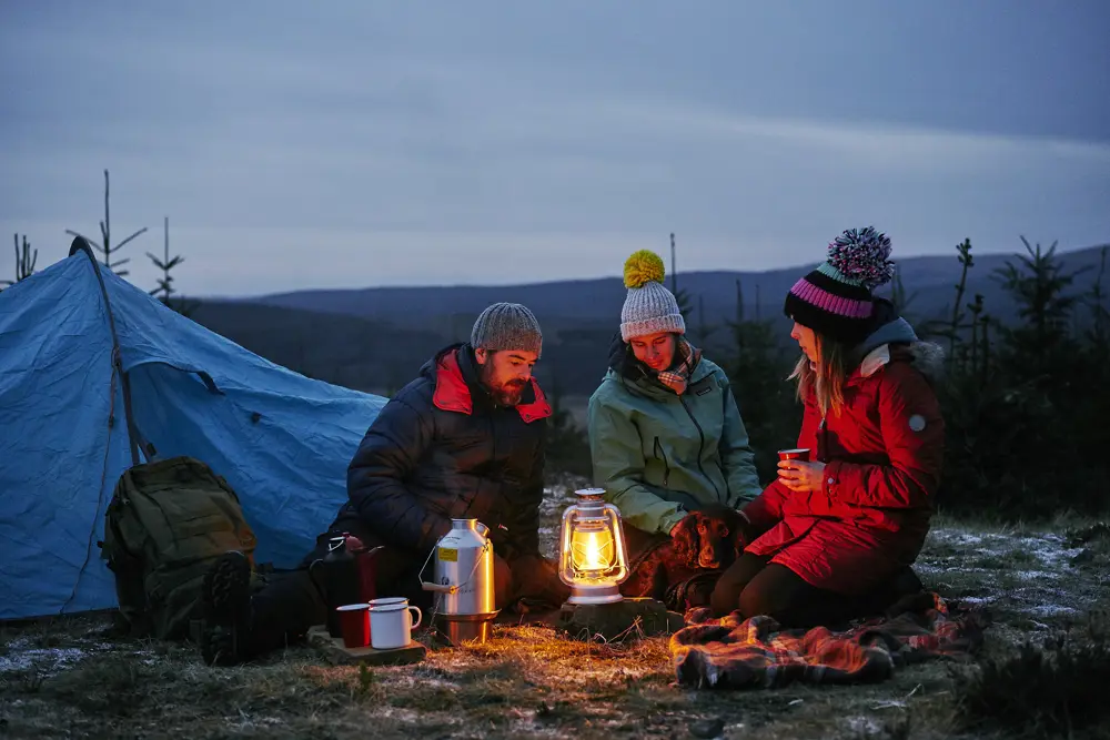 Three friends camping under the night sky