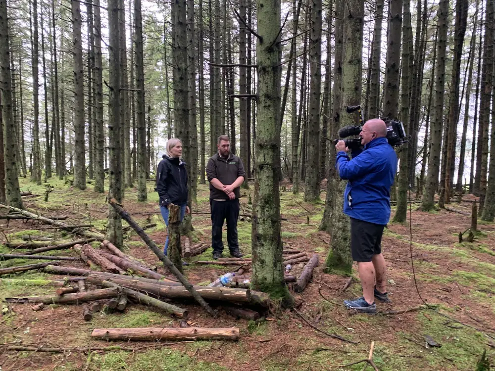 Staff member talking to camera crew in a forest
