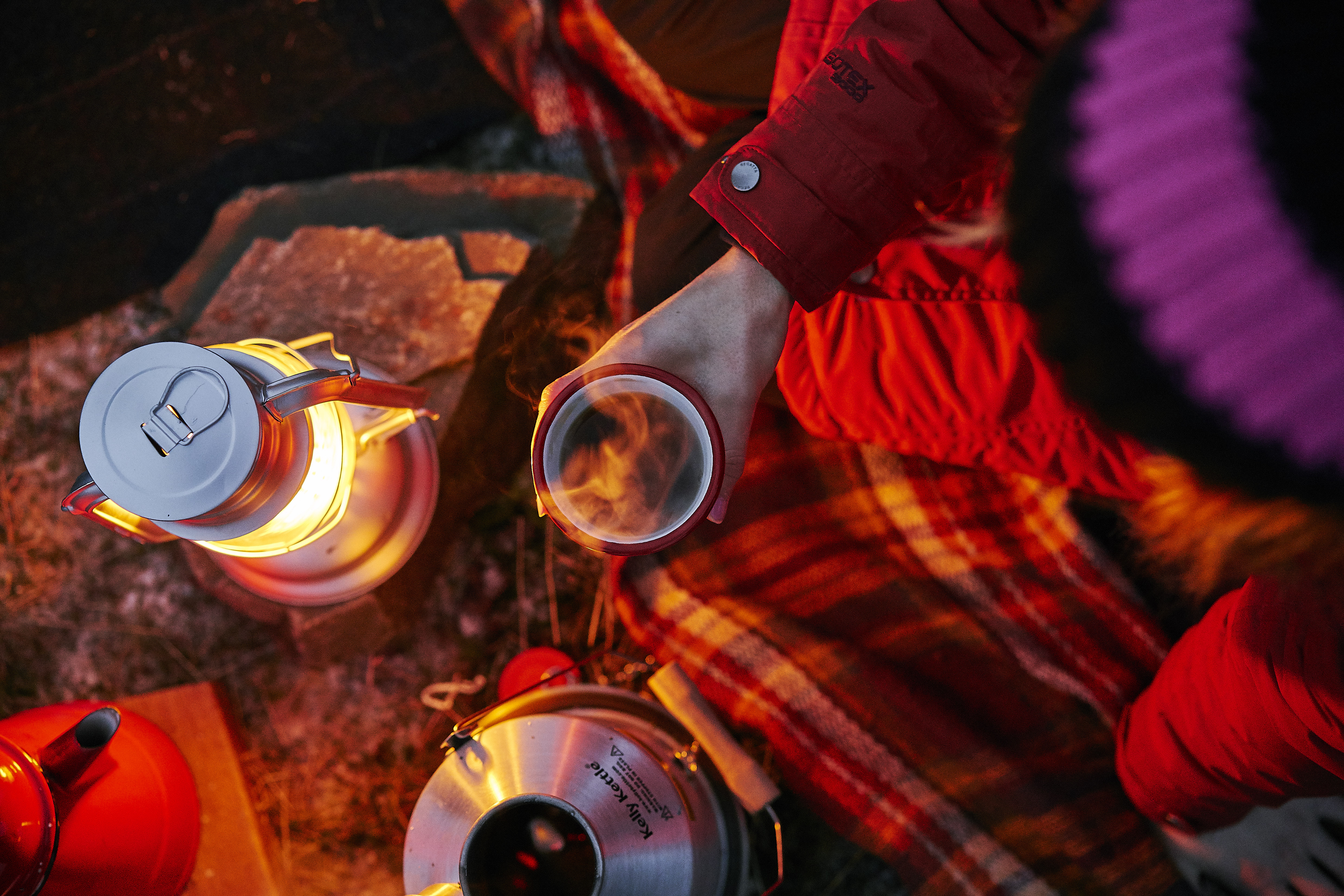 Campers sharing coffee near a fire