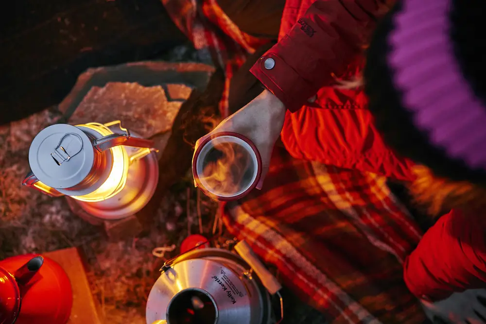 Campers sharing coffee near a fire