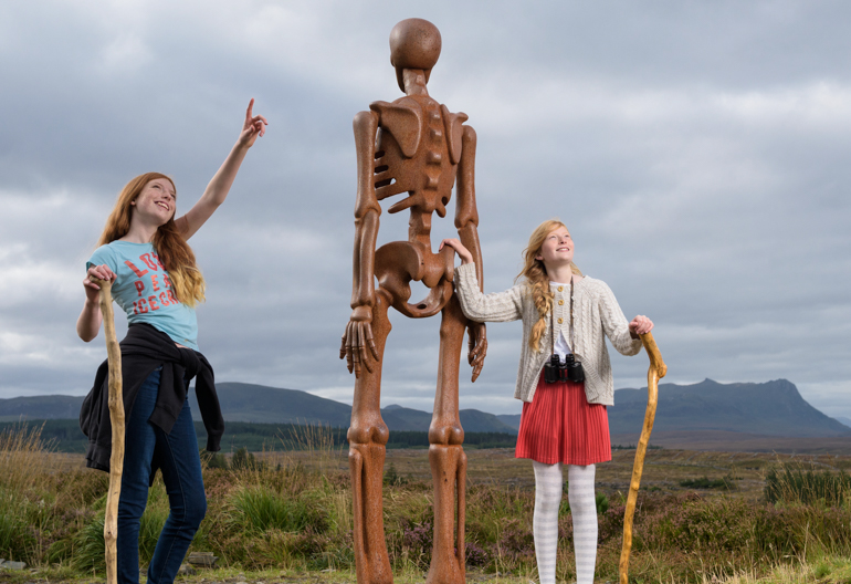 Two young girls inspect sculpture The Unknown, Borgie Glen, Sutherland